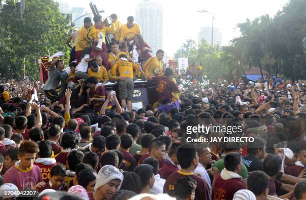 Philippino Catholics climb over one another to touch and kiss the Black Nazarene, a life-size icon of Jesus Christ carrying a cross during the annual...