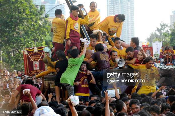 Philippino Catholics climb over one another to touch and kiss the Black Nazarene, a life-size icon of Jesus Christ carrying a cross during the annual...