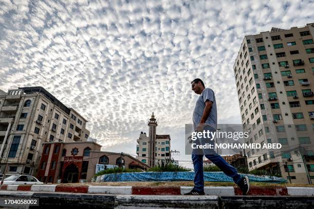 Man takes an early morning walk with a cup of coffee along a street in Gaza City on October 3, 2023.