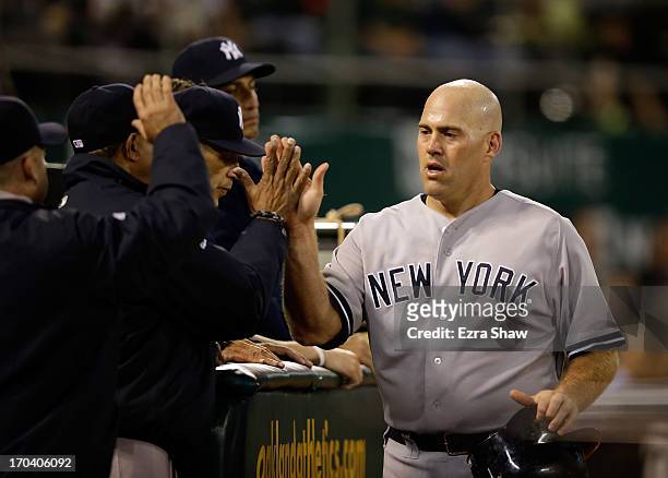 Kevin Youkilis of the New York Yankees is congratulated by teammates after he scored in the seventh inning of their game against the Oakland...