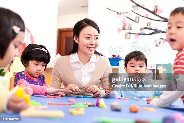 kindergarten teacher and children playing with plasticine - surrounding support stock pictures, royalty-free photos & images