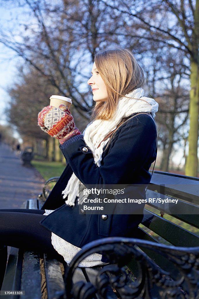 Woman having coffee on park bench