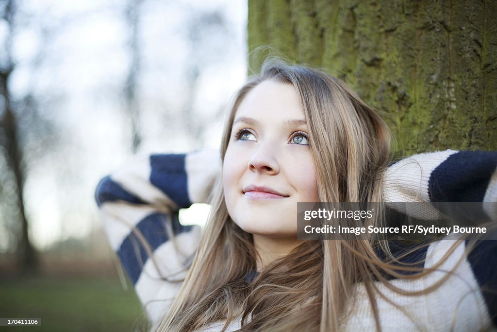 Woman sitting by tree outdoors