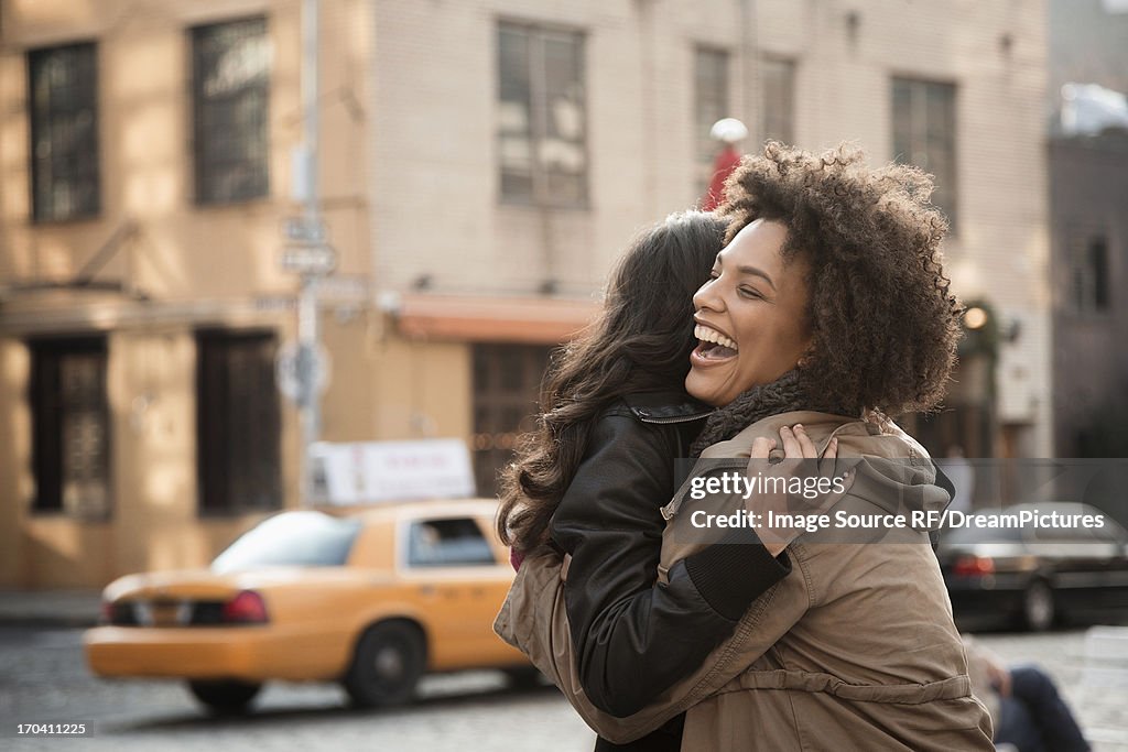 Women hugging on city street