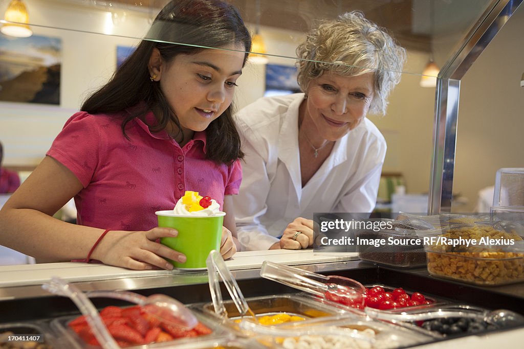 Girl putting toppings on frozen yogurt