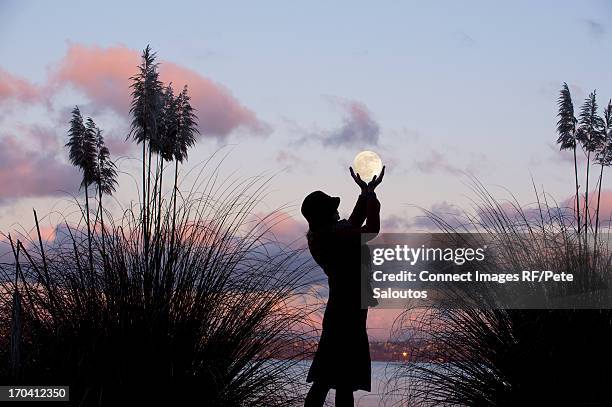 woman cupping hands around moon - luna llena fotografías e imágenes de stock