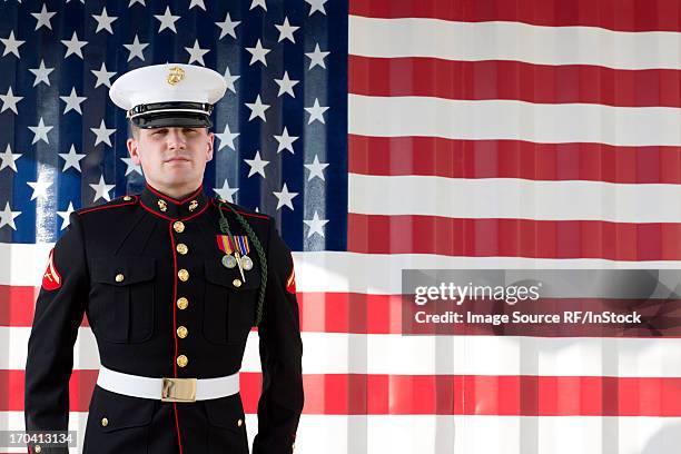 serviceman in dress blues by us flag - marine corps flag stockfoto's en -beelden