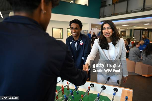 Britain's Home Secretary Suella Braverman greets her opponents ahead of a game of table football during a visit to Bolton Lads and Girls Club on...
