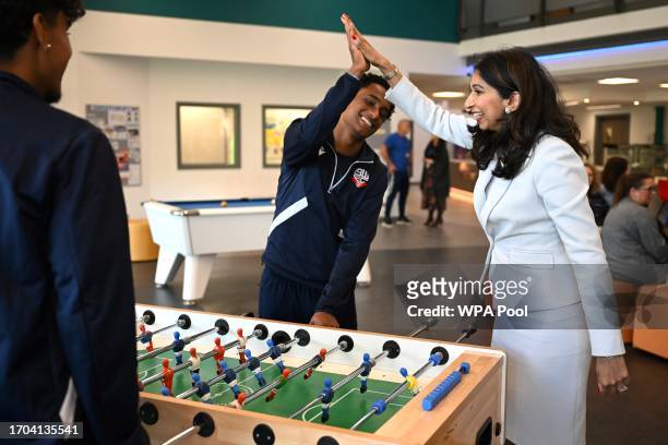 Britain's Home Secretary Suella Braverman high-fives her teammate while playing table football during a visit to Bolton Lads and Girls Club on...