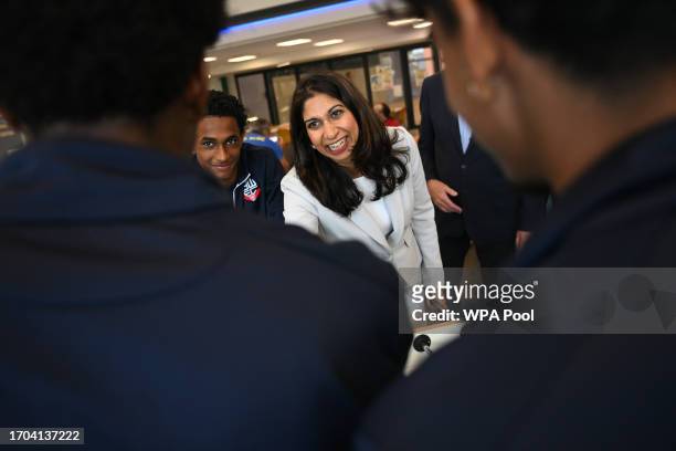 Britain's Home Secretary Suella Braverman shakes hands at the end of a game of table football during a visit to Bolton Lads and Girls Club on October...