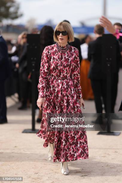 Anna Wintour is seen outside Dior show wearing black sunnies, lilac crystal necklace, red and white colored patterned long dress and snake print...