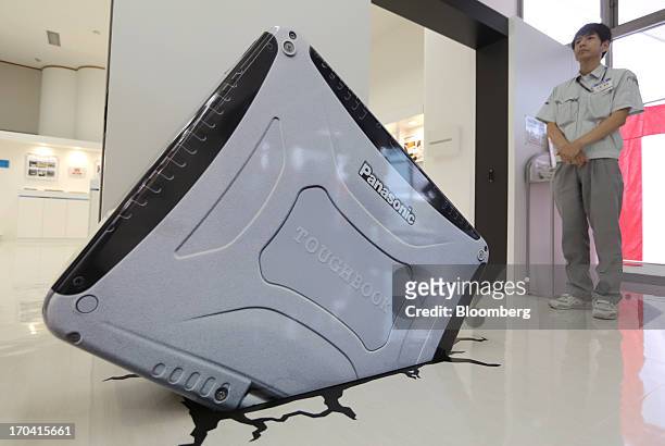 An employee stands next to a mock oversized Panasonic Corp. Toughbook laptop computer displayed in a show room at the company's plant in Kobe City,...