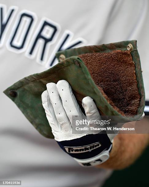 Kevin Youklis of the New York Yankees holds onto the wearing Franklin batting gloves holds onto the pinetar rag in the dugout against the Oakland...