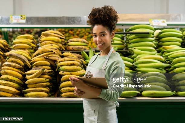happy retail clerk making an inventory at the supermarket - plantain stock pictures, royalty-free photos & images