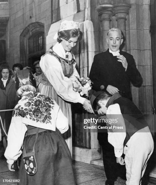 Princess Margaretha of Sweden in national costume receives a bouquet from twins Eva and Lars Sorensen, on her arrival at the Swedish Church Hall...