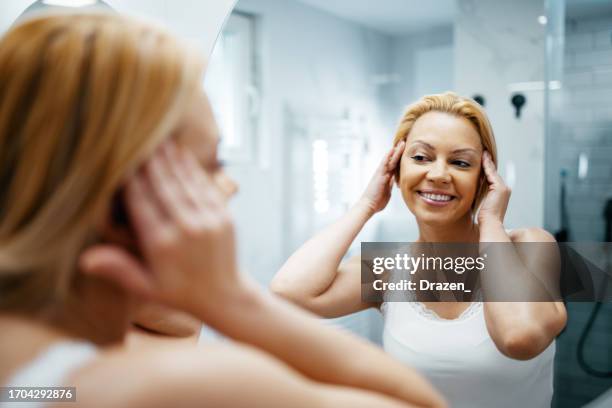 aging woman in front of the mirror looking at wrinkles and smiling - makeup before and after bildbanksfoton och bilder