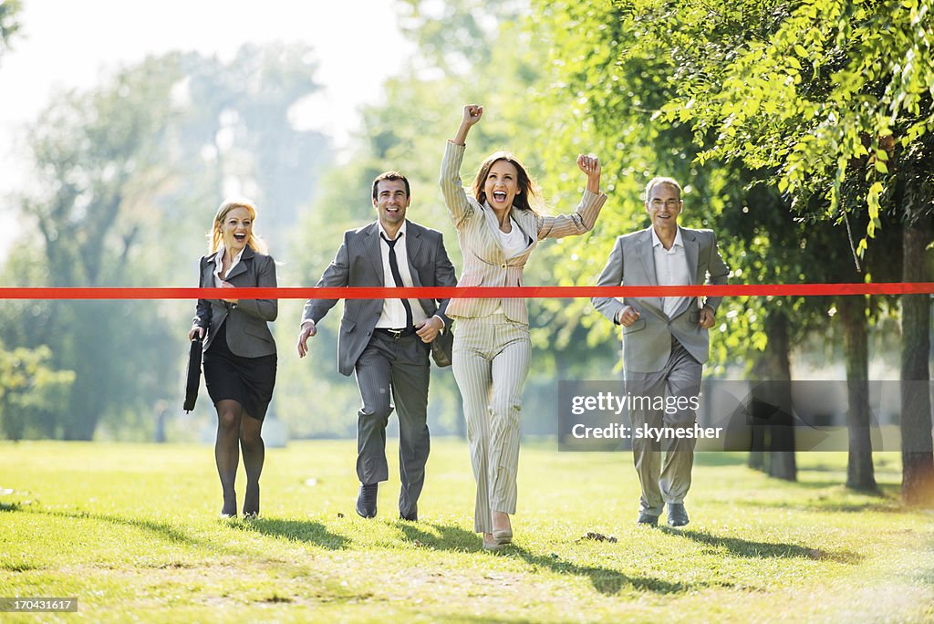 Business people running to finish, crossing red line