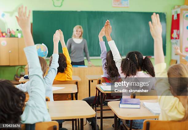 children with raised hands in classroom - children raising their hands stock pictures, royalty-free photos & images