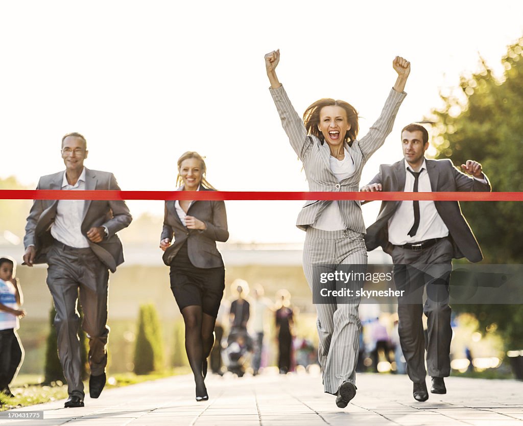 Business people running to finish, crossing red line.