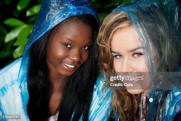 two women in blue plastic rain poncho's - rain poncho stockfoto's en -beelden