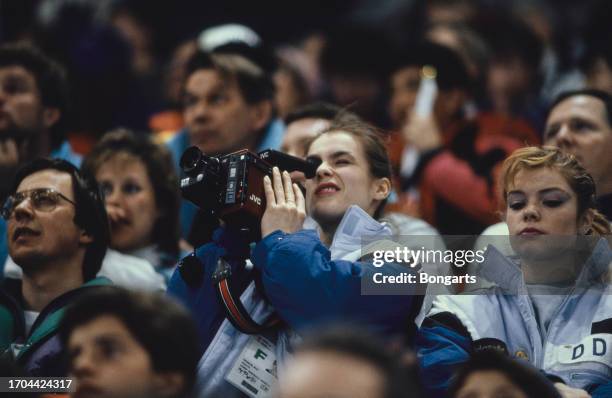 German figure skater Katarina Witt uses a JVC video camera as she sits in the spectators during the speed skating competition of the 1988 Winter...