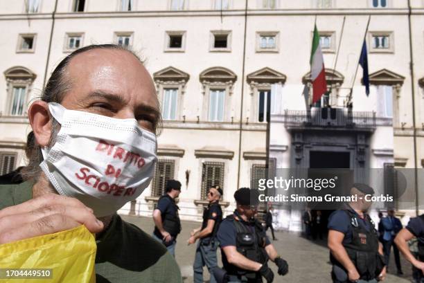 Workers belonging to the USB union in front of Palazzo Chigi guarded by the police wear masks on their face with the slogan "right to strike" on...