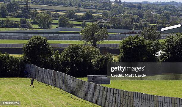 Man walks besides fences in empty fields at the Glastonbury Festival of Contemporary Performing Arts site at Worthy Farm, in Pilton on June 13, 2013...