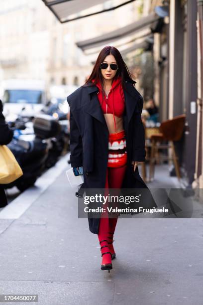 Guest is seen wearing black sunglasses, a blue long trench, black heels, red tights, a red skirt with a mouth printed on and a red cropped hoodie...