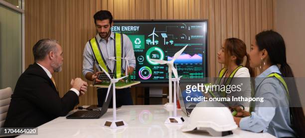 gruppe von energieingenieuren, die im besprechungsraum über ein windturbinenprojekt diskutieren - green economy stock-fotos und bilder