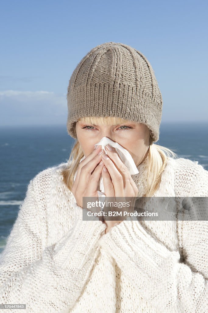 Young Woman Sneezing Into A Tissue