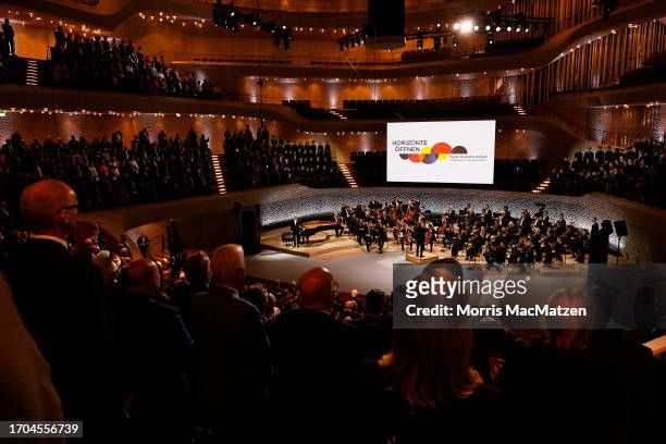 People stand as the national anthem is played during a ceremony in Hamburg's Elbphilharmonie opera house as part of the celebrations on German Unity...
