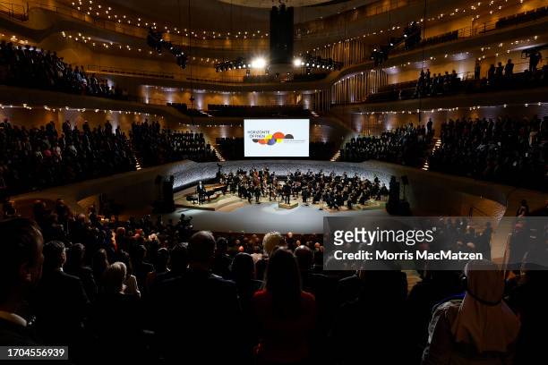 People stand as the national anthem is played during a ceremony in Hamburg's Elbphilharmonie opera house as part of the celebrations on German Unity...