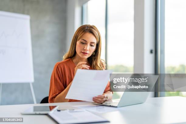 jeune femme d’affaires heureuse et prospère travaillant avec des documents à l’intérieur du bureau. - woman reading photos et images de collection