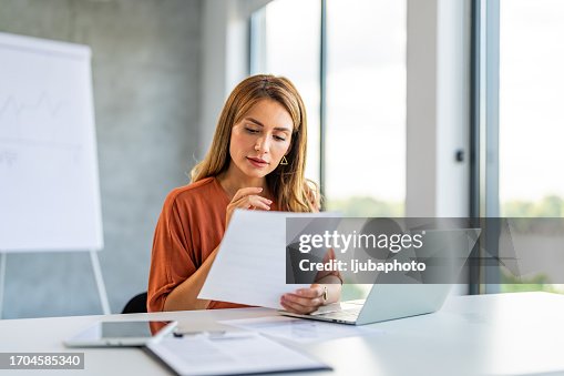 Young happy and successful businesswoman working with documents inside office.
