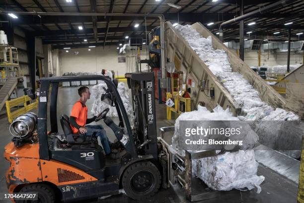 Worker loads recycled plastics on a conveyor belt for processing at the Trex manufacturing facility in Winchester, Virginia, US, on Wednesday, June...