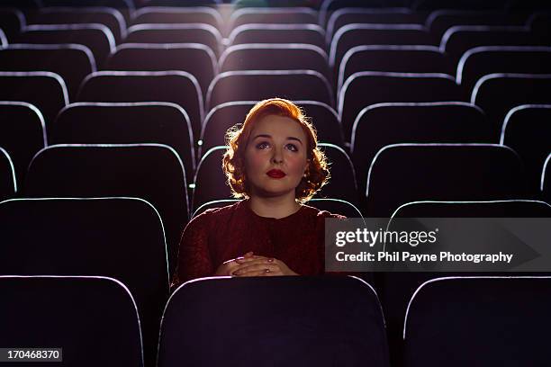 redhead woman sitting alone in cinema - salle de cinema photos et images de collection