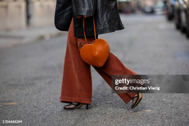 Joicy Muniz wears black oversized leather jacket, brown Alaia heart bag, flared rust brown pants, necklace during the Womenswear Spring/Summer 2024...