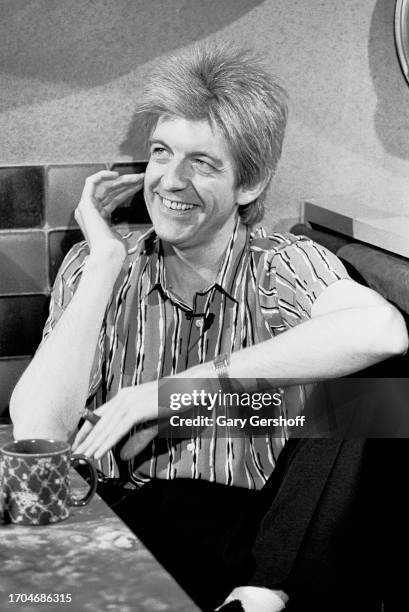 View of English New Wave and Pop musician Nick Lowe, a cigar in his hand, sits a diner table during an interview on MTV, New York, New York, June 14,...