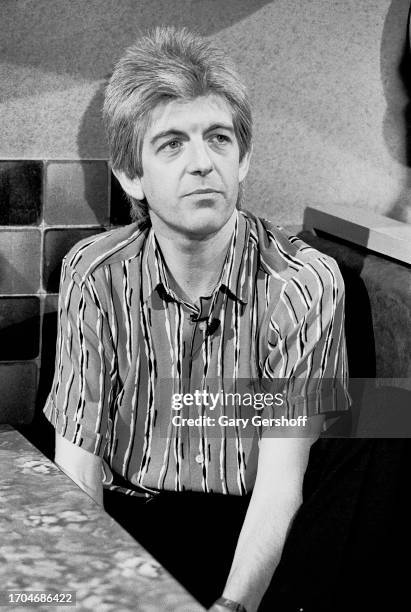 View of English New Wave and Pop musician Nick Lowe sits a diner table during an interview on MTV, New York, New York, June 14, 1983.