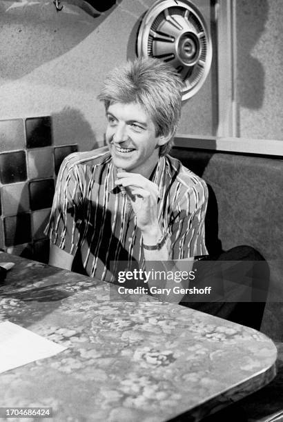 View of English New Wave and Pop musician Nick Lowe, a cigar in his hand, sits a diner table during an interview on MTV, New York, New York, June 14,...