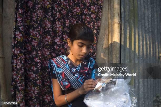 Ritu reads in class seven in Uchutia High School. After school she earns money by sewing clothes to support her family. Manikganj, Bangladesh,...