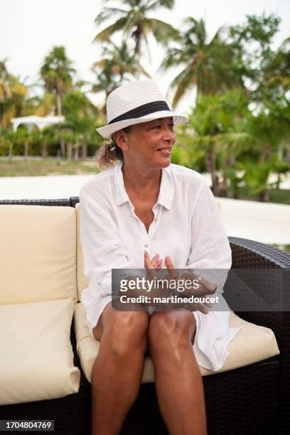 hermosa mujer 50+ fumando un cigarro en un entorno tropical. - beautiful women smoking cigars fotografías e imágenes de stock