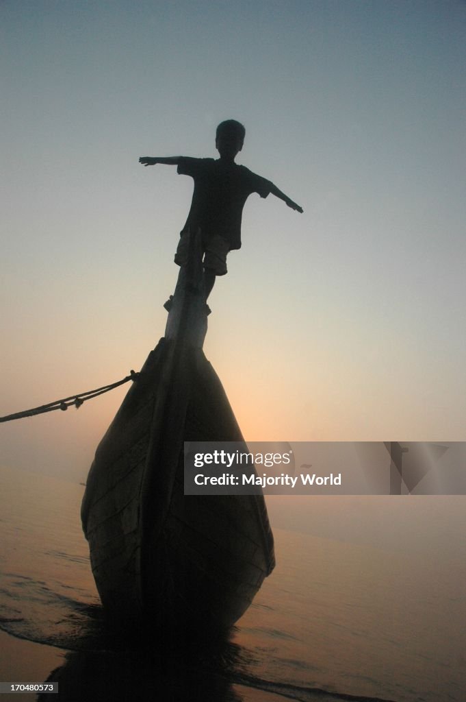 A silhouette of a child on a boat, on the shores of the Bay of B