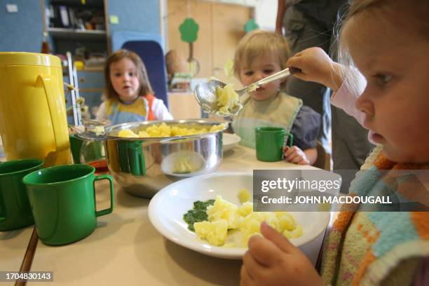 Toddler of the "Frogs" group helps herself to potatoes during lunch at the Spreekita Kindergarten in Berlin 03 May 2007. AFP PHOTO JOHN MACDOUGALL