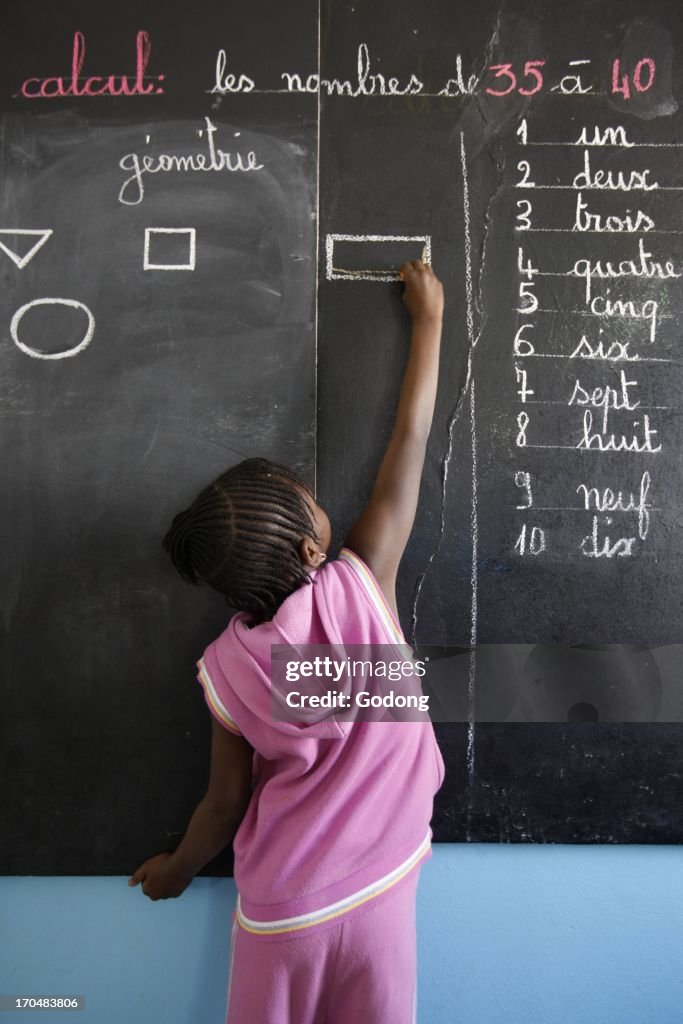 Primary schoolgirl writing on the blackboard