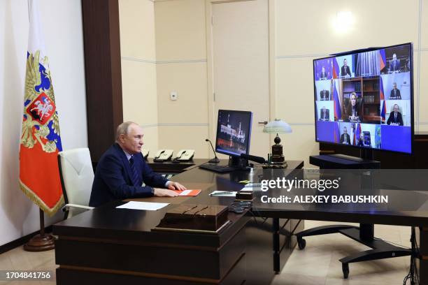 This pool photograph distributed by Russian state owned agency Sputnik shows Russian President Vladimir Putin chairing a Security Council meeting via...