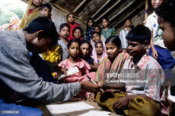 Ex garment worker children at a BRAC school in Mirpur, Dhaka, sign for their Taka 300 monthly stipend for attending school. Bangladesh. Education is...