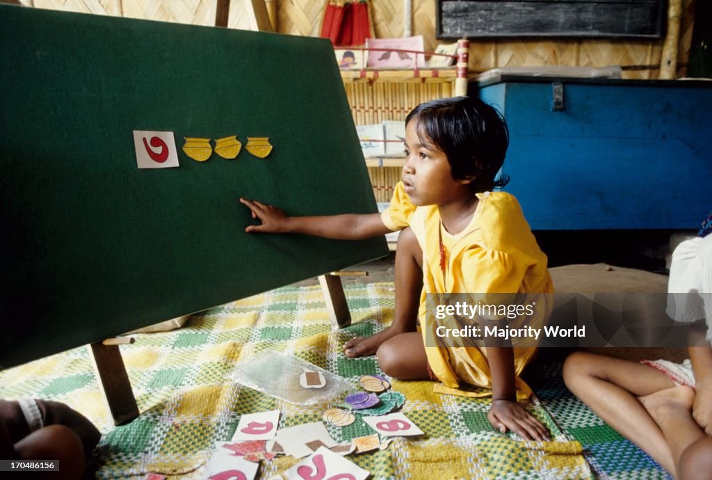 A girl child learning numbers at a class of a non formal school,