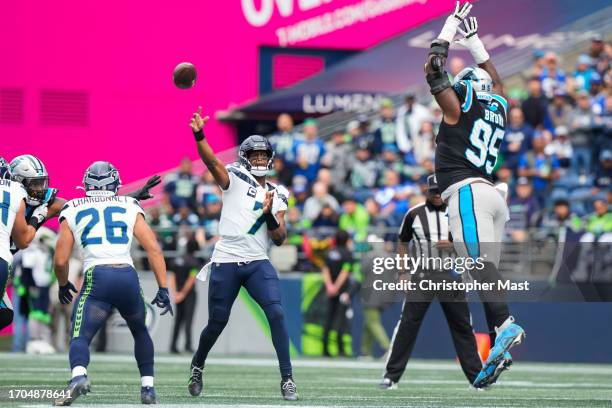 Geno Smith of the Seattle Seahawks throws a pass while Derrick Brown of the Carolina Panthers tries to knock it down during the first half at Lumen...