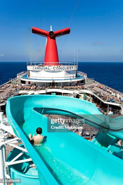 Cruise ship Lido deck with sun and swimming pool, passengers enjoying the sun bathing and sunshine, Boy sliding down water slide sitting up, cruise...